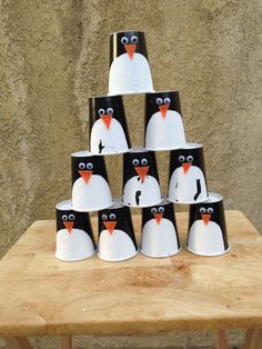 a group of penguin cups sitting on top of a wooden table next to a wall