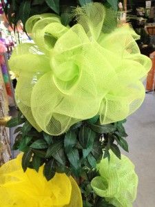 yellow and green mesh flowers are on display in a flower shop, with other items behind them