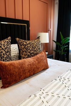 a bed topped with pillows next to a lamp