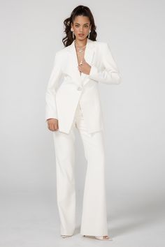 a woman in a white suit posing for the camera with her hands on her hips