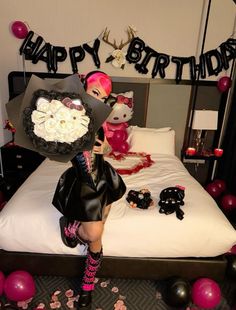 a woman sitting on top of a bed in a room with balloons and streamers