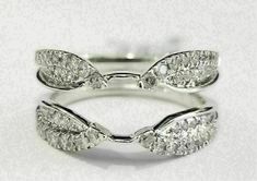 a white gold ring with three leaves on it, and two diamonds in the middle