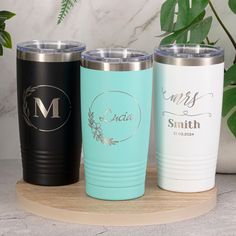 three personalized tumblers sitting on top of a wooden tray next to a potted plant