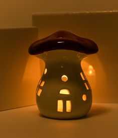 a small white vase with a red hat on it's head sitting in front of a wall