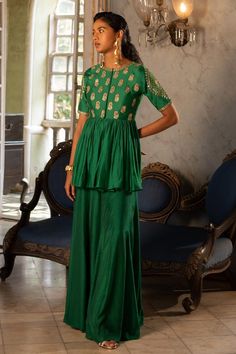 Emerald green chiniya silk padded peplum with antique tone gold sequins and zari embroidery in floral patterns. Comes with cotton silk base palazzo.
Components: 2
Pattern: Embroidered
Type Of Work: Floral
Neckline: Round
Sleeve Type: Short
Fabric: Peplum : Chiniya silk, Palazzo : Cotton silk
Color: Emerald Green
Other Details: 
Peplum:
Padded
Floral buttis
Attached lining top yoke
Palazzo:
Attached lining
Karigari time: 50 hrs
Occasion: Destination Wedding - Aza Fashions Cotton Palazzo Pants, 1950’s Fashion, Zari Embroidery, Dress And Jacket Set, Indian Clothes, Indian Fashion Designers, Silk Pants, Gold Sequins, India Fashion