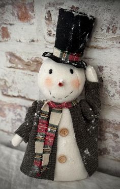 a snowman with a hat and scarf on it's head is standing next to a brick wall