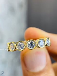 a person holding a yellow gold ring with three diamonds on it's sides and the middle