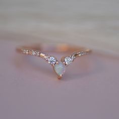 a white opal and diamond ring sitting on top of a table