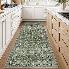 a kitchen with white cabinets and wooden flooring, along with a green runner rug