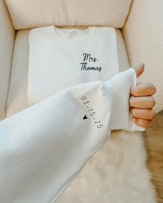 a woman's hand holding up a white t - shirt with mrs thomas written on it