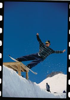 a man riding a snowboard down the side of a wooden ramp in the snow