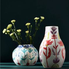 two vases with flowers in them on a table