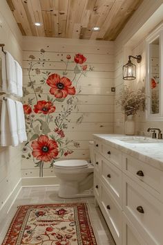 a bathroom decorated in white with red flowers on the wall and wooden ceilinging, along with an area rug