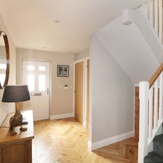 an empty room with white walls and wooden floors, along with a lamp on the floor