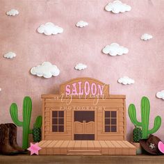 a paper cutout of a saloon surrounded by cactus