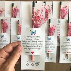 a person holding up some pink flowers in front of small cards with words on them