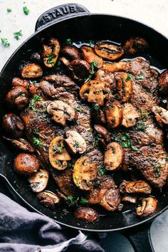 a skillet filled with meat and mushrooms