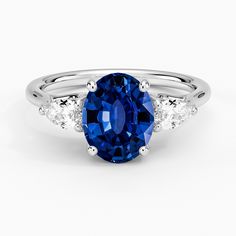 an oval blue sapphire and diamond ring with three side stones on the band, set in 18k white gold