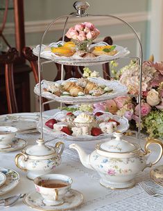 an assortment of tea and pastries on a table with pink flowers in the background