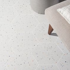 a living room with white and blue speckles on the floor, gray couch and chair