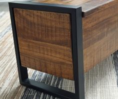 a close up of a wooden table with metal legs on carpeted area next to rug