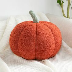 a large orange pumpkin sitting on top of a white blanket