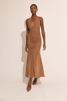 a woman in a tan dress poses for the camera