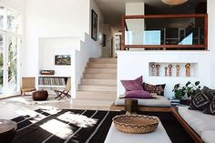 a living room filled with lots of furniture next to a stair case in front of a window