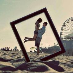 two people standing in the sand near a ferris wheel