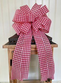 a red and white gingham bow sitting on top of a wooden table next to a wall