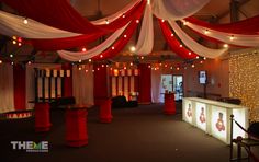 a room decorated with red and white drapes, lights, and curtains on the ceiling