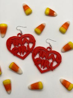 two heart shaped earrings with candy corn in the background