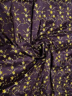 the fabric is purple with yellow flowers on it and has small white dots in the center