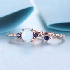 an opal and diamond ring on a white surface with blue stones in the middle