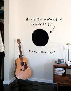 there is a guitar on the floor in front of a wall that says, help to another universe come down