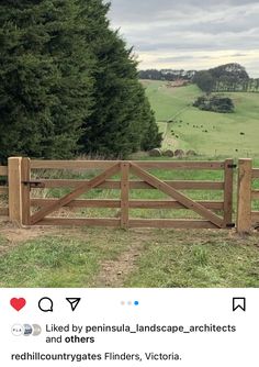 a wooden fence in front of a lush green field with trees on the other side