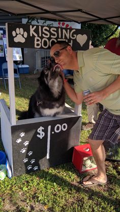 a man kissing his dog in front of a booth