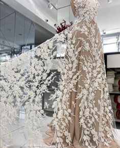 a dress on display in front of a glass case with white flowers and leaves all over it