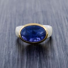 This ring is one of a kind fully made of 925 sterling silver with high quality craftsmanship.  The band which is main highlight of the ring , as its has a matte scratched design band which is done very professionally and takes time. The collet is of pure solid gold vermeil which gives ring a two tone look. Gemstone: Natural Tanzanite AAA quality 10 carat / 11mm x 15mm Facts About Vermeil Jewelry: Is gold vermeil good quality? After solid gold, gold vermeil is the highest quality type of gold ton Timeless Tanzanite Rings For Gifts, Timeless Tanzanite Rings As Gift, Tanzanite Bezel Set Ring, Modern Oval Tanzanite Ring, Polished Tanzanite Sapphire Ring, Sapphire Tanzanite Ring With Polished Finish, Timeless Silver Tanzanite Jewelry, Timeless Silver Tanzanite Rings, Modern Tanzanite Gemstone Ring