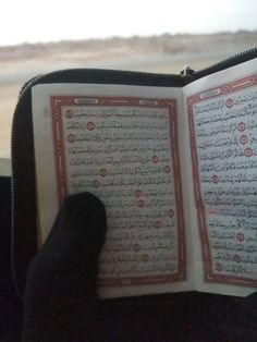 a person holding an open book in their hand with arabic writing on the pages and inside