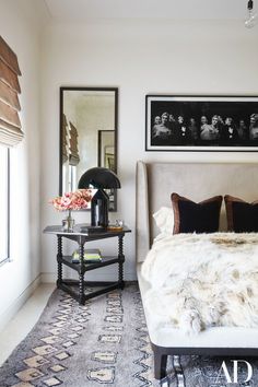 a white bed sitting next to a window in a room with pictures on the wall