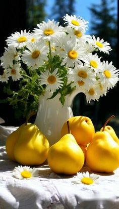 some yellow pears and white daisies in a vase on a table with flowers