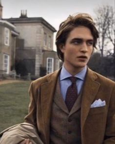 a man wearing a suit and tie sitting in front of a house