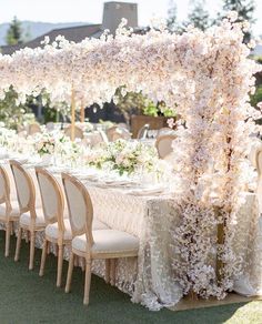 an outdoor wedding setup with white flowers on the table and chairs in front of it