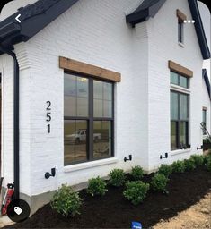 a white brick house with black trim and windows