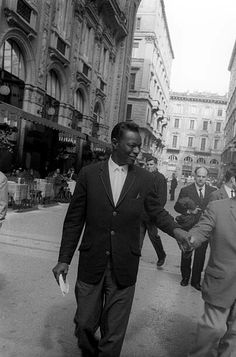 black and white photograph of two men in suits walking down the street holding hands with each other