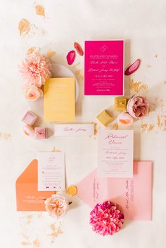 the wedding stationery is laid out on top of each other, including pink and yellow flowers