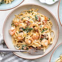 four plates of pasta with shrimp and spinach