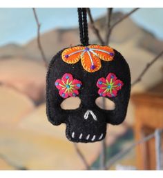 a black skull hanging from a tree with colorful flowers on it's head and eyes