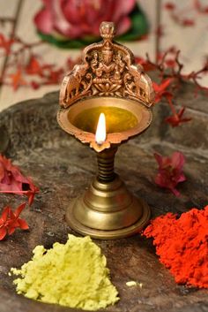 a small metal candle holder sitting on top of a rock next to some colorful powder